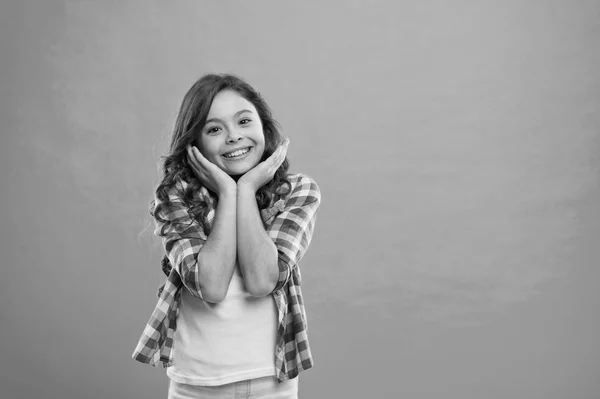 Niño feliz cara linda con adorable pelo rizado de pie sobre fondo azul. Pura belleza. Consejos de belleza para el cabello ordenado. Niña larga y saludable pelo brillante llevar ropa casual. Niña con el pelo largo —  Fotos de Stock