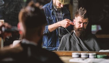 Hipster istemci Başlarken saç kesimi. İstemci ense üzerinde kırpma makası kesme saçlı berber. Hippi saç modeli kavramı. Sakallı adam berber arka plan saçına Kuaför Saç kesme makinesi ile çalışır