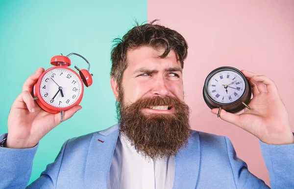 Does changing clock mess with your health. Man bearded hipster hold two different clocks. Guy unshaven puzzled face having problems with changing time. Time zone. Changing time zones affect health — Stock Photo, Image