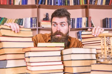 Öğretmen ya da öğrenci sakallı defocused kitaplar ile masada oturur. Adam Kitaplığı'nda, eğitim sırasında kitaplar, kitap rafı arka plan üzerinde yığınları arasında şok yüzünde. Kazık kavramı