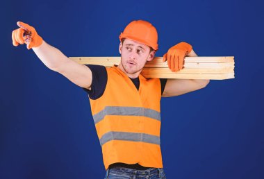 Ahşap malzemeler kavramı. Marangoz, woodworker, meşgul yüz taşıdığı ahşap kiriş omuz üzerinde güçlü Oluşturucu. Adam kask, kask ve yön, mavi arka plan işaret koruyucu eldivenler