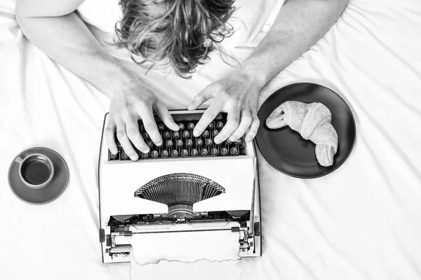 Man typing retro writing machine. Old typewriter on bedclothes. Male hands type story or report using vintage typewriter equipment. Writing routine. No day without chapter. Vintage typewriter concept