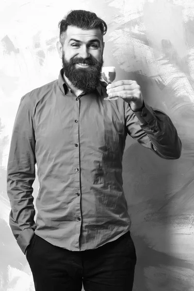Hombre barbudo, barba larga. Brutal caucásico sonriendo hipster feliz con bigote en camisa marrón sosteniendo tiro rojo alcohólico en fondo de textura colorida — Foto de Stock