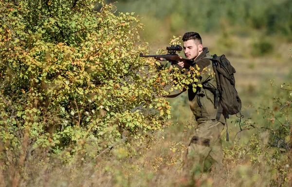 Hunter hold rifle. Man wear camouflage clothes nature background. Hunting permit. Hunting is brutal masculine hobby. Hunting equipment for professionals. Bearded serious hunter spend leisure hunting