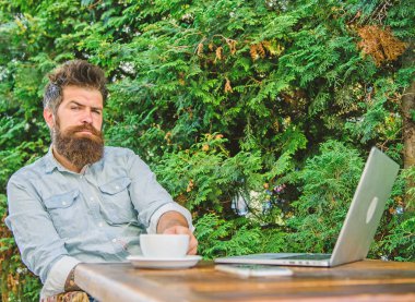 Adam kahve rahatlatıcı Teras yeşil dallar arka plan içer. Hoş bir an. Düşünmek için zaman ayırın. Dinlenmek için mola. Sakallı adam hipster yapmak için kahve içmek duraklatmak ve dizüstü bilgisayar ile oturup süre düşünüyorum