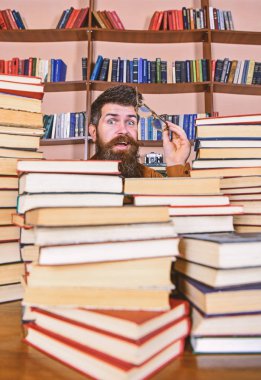 Öğretmen ya da öğrenci sakallı gözlük takmaz, defocused kitaplar ile masada oturur. Bilimsel araştırma kavramı. Adam kazık kitap Kütüphane, kitap rafı arka plan üzerinde arasında sürpriz yüzünde