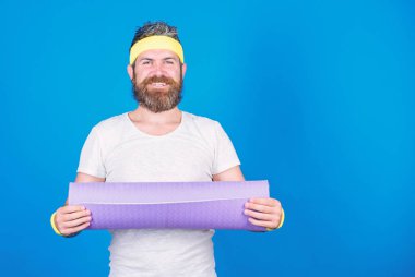 Atlet profesyonel yoga koç eğitim için motive. Adam atlet tutun fitness mat mavi renkli sakallı. Yoga sınıfında bir başlangıç sağlar. Yoga hobi ve spor olarak. Her gün pratik yoga. Formda kalmak