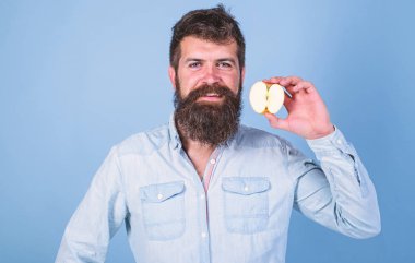 Adam gülümseyen tutan apple mavi arka plan sakallı. Yarım elma sağlıklı yaşam tarzı. Besin değeri kavramı. Vitamini beslenme diyet sağlık. Hipster doğal ekolojik elma gösterir