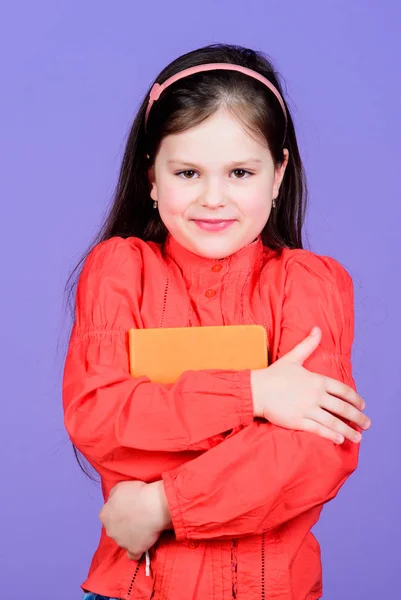 Che libro interessante. Carina la ragazzina che tiene un libro di finzione. Adorabile bambino della scuola con libro di attività. I piccoli scolari hanno preso il libro da biblioteca — Foto Stock