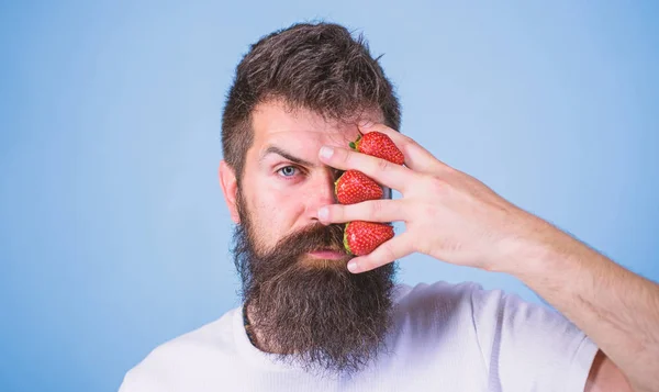 Hipster beard mustache thoughtful face think berries. Man can not think about anything but strawberry blue background. Strawberry on my mind. Man bearded hipster hold hand with strawberries near face