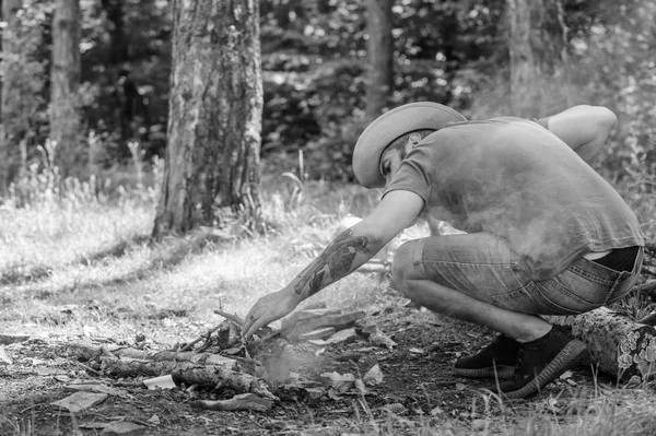 Guía definitiva de hogueras. Coloca las ramitas de madera o palos de madera de pie como una pirámide y coloca las hojas debajo. Sombrero de paja hombre prepara hoguera en el bosque. Cómo construir hogueras al aire libre — Foto de Stock