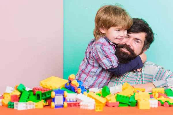 Importance of playing together. Child care concept. Happy family. Child development and upbringing. Father and son have fun. Bearded hipster and boy play together. Dad and child build plastic blocks
