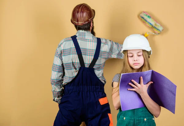 Casa de remodelação familiar. Ajudante de pais pequenos. Pai barbudo homem e filha chapéu duro capacete uniforme renovando casa. Atividade de melhoria em casa. Miúda a planear renovação. Quarto de renovação infantil — Fotografia de Stock