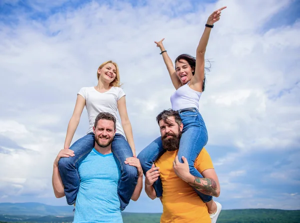 Fun times. Happy men piggybacking their girlfriends. Loving couples having fun activities outdoor. Loving couples enjoy fun together. Playful couples in love smiling on cloudy sky — Stock Photo, Image