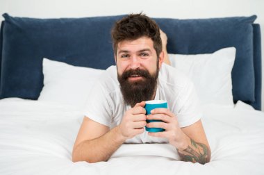 Rahatla ve dinlen. Enerji dolu. Kahve vücudu etkiler. Adam yakışıklı hipster kahve fincanı ile yatakta rahatlatıcı. Sakallı hipster sabah kahvesi tadını çıkarın. Sabah iyi kahve ile çok daha iyi olur