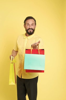 Müşteri için ikramiye teklif et. Olgun sakallı, neşeli yüzlü bir adam alışveriş torbaları tutuyor. Adamın beklenmedik yetenekleri var. Hediye sarısı arka plana şaşıran adam. Hediyeler hayatımızı daha ilginç kılıyor.