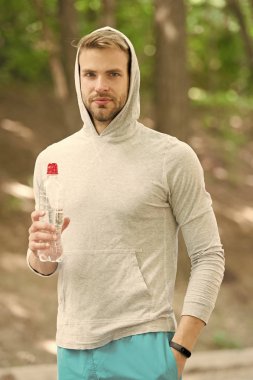 Harika bir egzersizden sonra vitamin içeceğini tazeliyorum. Adam atletik görünüşte su şişesi tutuyor. Sporcu parktaki eğitimden sonra su içer. Sporcu erkek sporcu idmandan sonra şişeye su döker.