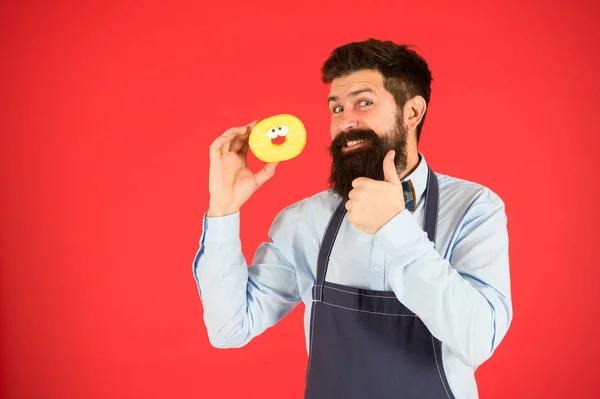 Bakker houd donut vast. Grappige hipster. Zoete donut. Chef-kok in café. Dieet en gezond voedsel. Donut dieet. Een calorie. Ik heb honger. Perfecte donut. Een man met baard in een schort. Donut eten. Trots op zijn gebak — Stockfoto