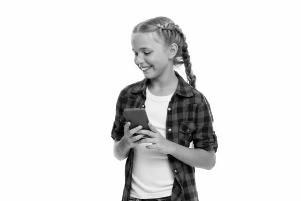 กําลังตรวจสอบแก็ดเจ็ทโทรศัพท์ของเธอ การพึ่งพาโทรศัพท์มือถือ เด็กผู้หญิงน่ารักเด็กเล็ก ๆ ยิ้มหน้าจอโทรศัพท์ การท่องอินเทอร์เน็ตและเครือข่ายสังคม โทรศัพท์มือถือและการเสพติดอินเทอร์เน็ตหรือความหมกมุ่น — ภาพถ่ายสต็อก