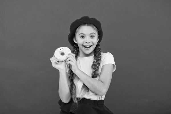 Girl hold glazed cute donut in hand red background. Kid smiling girl ready to eat donut. Sweets shop and bakery concept. Kids huge fans of baked donuts. Impossible to resist fresh made donut — Stock Photo, Image
