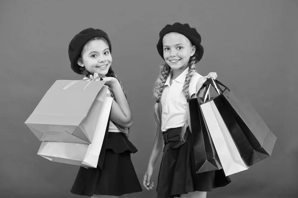 Winkelen plezier met beste vrienden geworden. Kinderen schattig schoolmeisjes houden bos boodschappentassen. Kinderen tevreden door winkelen rode achtergrond. Geobsedeerd met winkelen en winkelcentra kleding. Shopaholic concept — Stockfoto