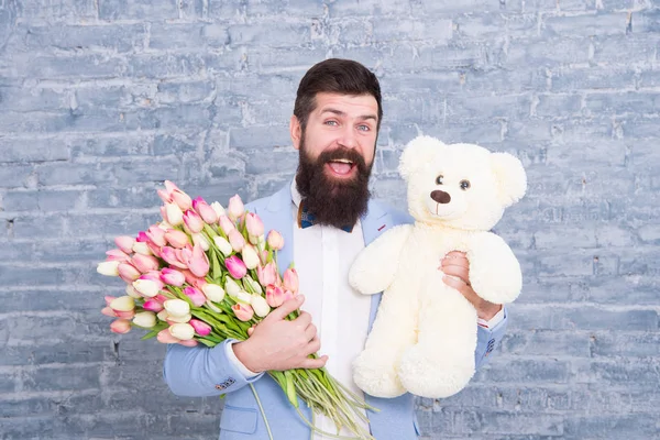 Eu sinto muito. Dia das mulheres. Amo-te tanto. 8 de Março. Um presente de primavera. Homem barbudo hipster com flores. Homem barbudo com buquê de tulipa e urso. Encontro amoroso. férias internacionais. Amor e romance — Fotografia de Stock