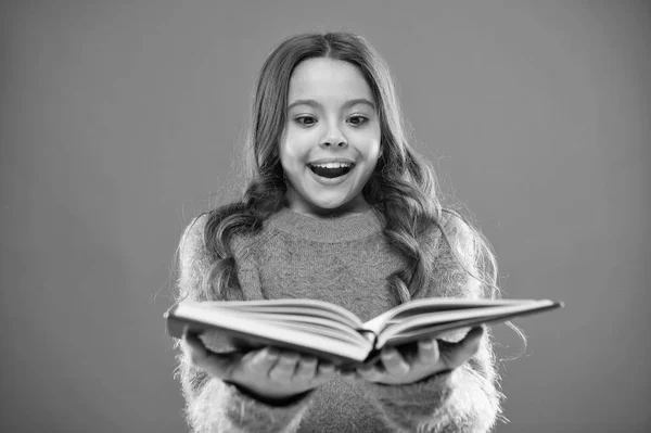 A los niños les gusta leer libros. Concepto de librería. Maravillosos libros gratuitos para niños disponibles para leer. Literatura infantil. Actividades de lectura para niños. Niña mantenga libro leer historia sobre fondo naranja — Foto de Stock