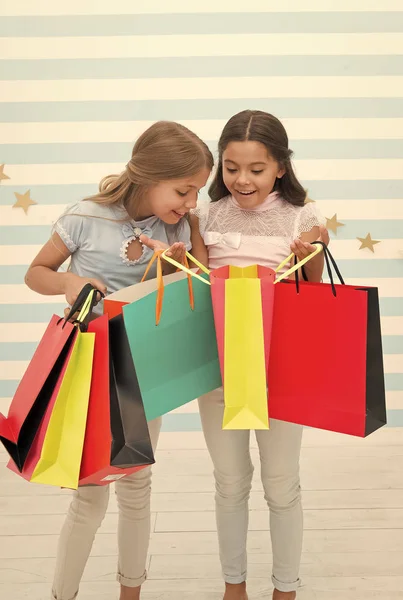 Svart fredag på skolmarknaden. glada små barn flickor med shoppingväskor efter svart fredag försäljning. små barn med köp från skolmarknaden. — Stockfoto