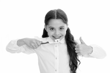 Her gün dişlerini fırçala. Ağız temizliği kavramı. Kız diş fırçasını tutuyor ve beyaz arka plan hareketlerini gösteriyor. Çocuk kız dişini macunla fırçaladı. Çocuk liseli çocuk diş hijyeni konusunda mutlu.