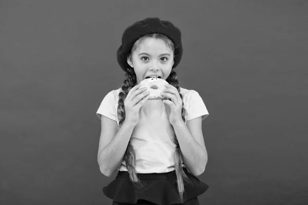 Delicioso donut doce. Menina em chapéu de boina segurar donut fundo vermelho. Miúdo menina brincalhão comer donut. Conceito de saúde e nutrição. Bela vida. Loja de doces e conceito de padaria. Garoto fã de rosquinhas assadas — Fotografia de Stock