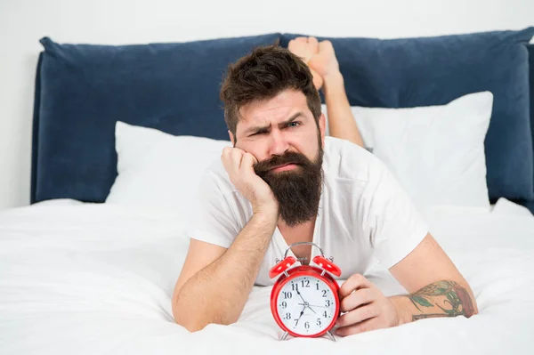 Hipster szakállas férfi feküdt az ágyban ébresztőórával. Ideje, hogy felébredjen. Miért kell ébredni korán minden reggel. Egészségügyi elónyei a korai emelkedő. Ébredezik korán ad több időt előkészítése és időszerű — Stock Fotó