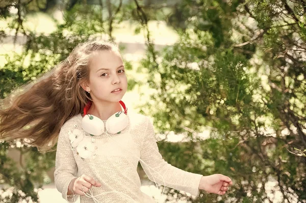 Baile infantil con música en el parque de verano. Niña disfrutar de la música en los auriculares al aire libre. Bailarina de cabellos largos. Sonido de melodía y mp3. Verano diversión y alegría — Foto de Stock