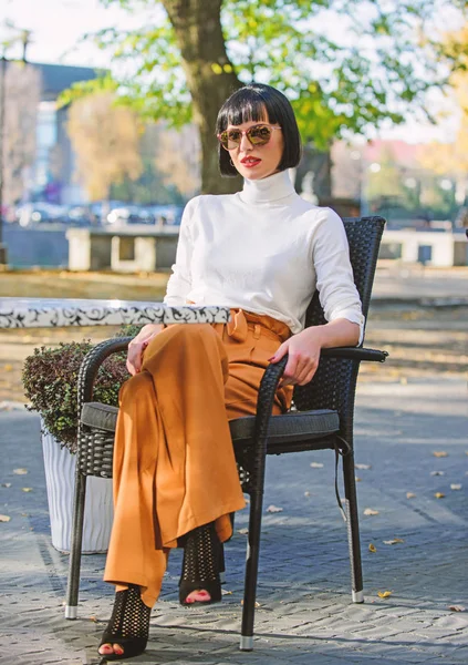 Mulher elegante morena sentar ao ar livre natureza fundo. Conceito de moda e estilo. Menina com maquiagem posando em roupas da moda. Roupa elegante senhora alta magro. Mulher relaxar em calças soltas — Fotografia de Stock