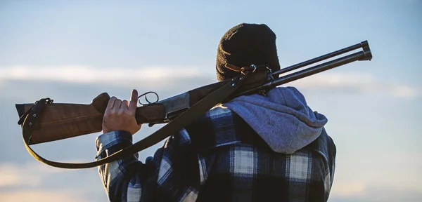 Brutalidad y masculinidad. Hunter lleva rifle en la mira trasera del hombro. Guy Hunter pasa tiempo libre cazando. Hombre tipo brutal guardabosques en el fondo de la naturaleza sombrero. Caza masculina hobby ocio concepto — Foto de Stock