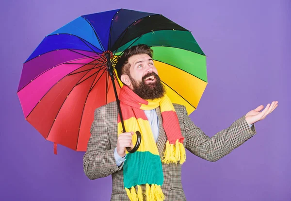 An umbrella is needed on a rainy day. Autistic or rain man holding colorful umbrella. Autism. Bearded man checking if it rains. Fashion man with colorful accessories. Let it rain