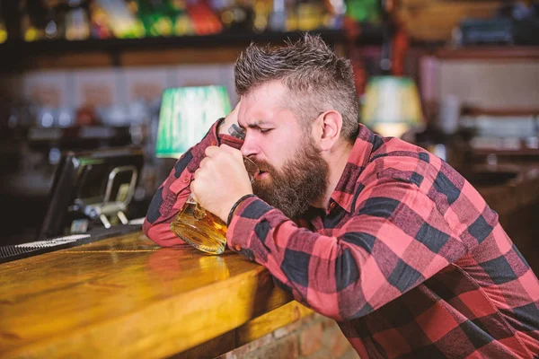 Man with beard spend leisure in dark bar. Brutal hipster bearded man sit at bar counter drink beer. Hipster relaxing at bar with beer. Order alcohol drink. Bar is relaxing place have drink and relax