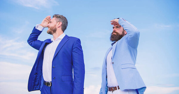 Развитие бизнес-направления. Бизнесмены с бородатыми лицами стоят спиной к заднему небу. Мужчины в костюмах смотрят в разные стороны. Меняю курс. Новые направления бизнеса
