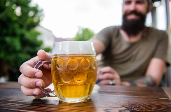 Criativa jovem cervejeira. A cerveja artesanal é jovem, urbana e elegante. Cultura de cerveja distinta. Caneca de cerveja fresca fria na mesa de perto. Homem sentar terraço café desfrutando de cerveja desfocada. Conceito de álcool e bar — Fotografia de Stock