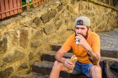 Adam sakallı hızlı atıştırmalık tadını çıkarın. Sokak yemekleri çok güzel. Kentsel yaşam tarzı ve sağlıksız beslenme. Kaygısız hipster merdivenlerde oturup abur cubur yer. Aç adam atıştırması. Abur cubur. Sosisli yiyen adam