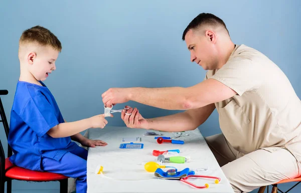 Ο άνθρωπος γιατρός κάθεται επιτραπέζια ιατρικά εργαλεία εξέταση μικρό παιδί ασθενή. Παιδίατρος. Υγειονομική περίθαλψη. Φροντίδα παιδιών. Προσεκτική παιδίατρος έλεγχος της υγείας του παιδιού. Ιατρική εξέταση. Ιατρικές υπηρεσίες — Φωτογραφία Αρχείου