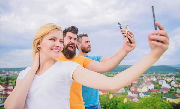 Hoy en día selfie. Mujer bonita y hombres sosteniendo teléfonos inteligentes en las manos. A la gente le gusta fotografiar selfies en el paisaje natural. Mejores amigos tomando selfie con el teléfono de la cámara. Compartir selfie en las redes sociales — Foto de Stock
