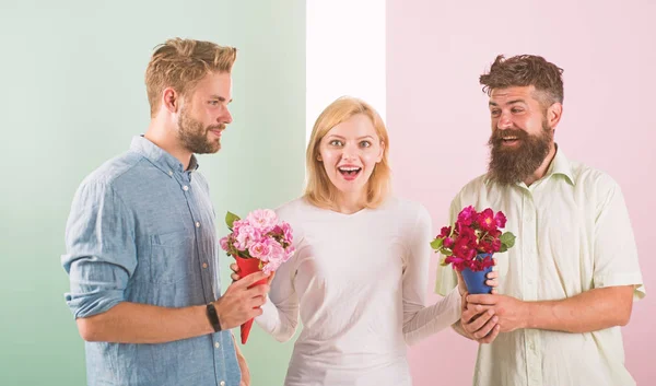 Girl popular receive lot men attention. Woman smiling can not choose partner, grabs both bouquets. Girl happy likes gifts. Love triangle. Men competitors with bouquets flowers try conquer girl — Stock Photo, Image