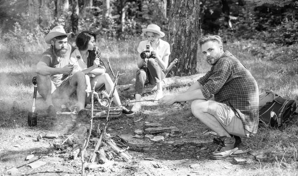 Los excursionistas se sientan cerca de la fogata relajándose mientras esperan asando comida. Los excursionistas organizaron un picnic rápido para comer y relajarse. Los excursionistas pasan el ocio en el fondo de la naturaleza forestal. Vacaciones de senderismo juvenil. Caminata ideas de picnic — Foto de Stock