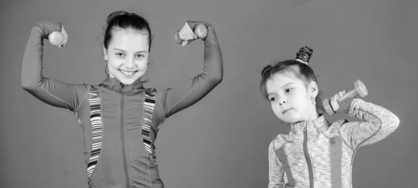 Прикольные милашки. Маленькие девочки пользуются фитнес-тренировки с гирями. Милые сестры делают гимнастические упражнения с гантелями. Маленькие дети развивают физическую форму. Спорт и фитнес для детей — стоковое фото