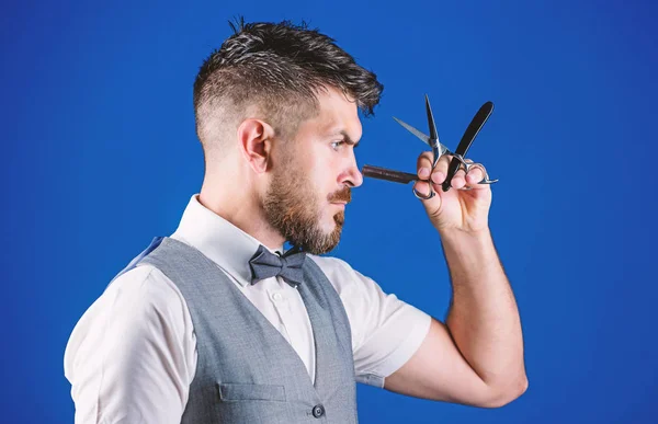 Haircuts and shaves. Bearded man with razor and scissors in retro barbershop. Hipster with beard in razor barber shop. Man with beard and mustache in shaving salon. Barber hold vintage barber tools