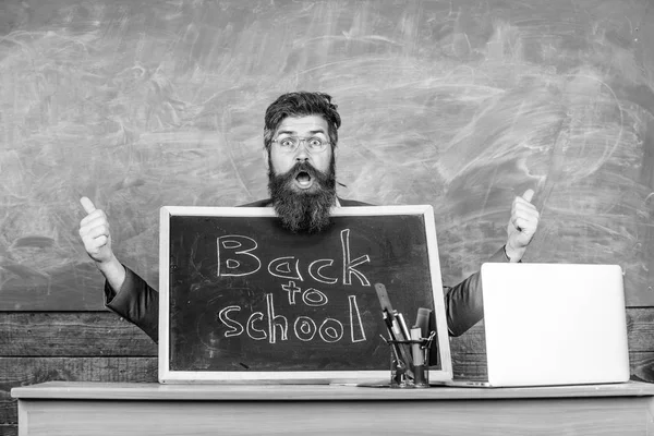 Beginning of new school year in september. Teacher welcomes new pupils to enter educational institution. Teacher or school principal welcomes with blackboard inscription back to school. Welcome back