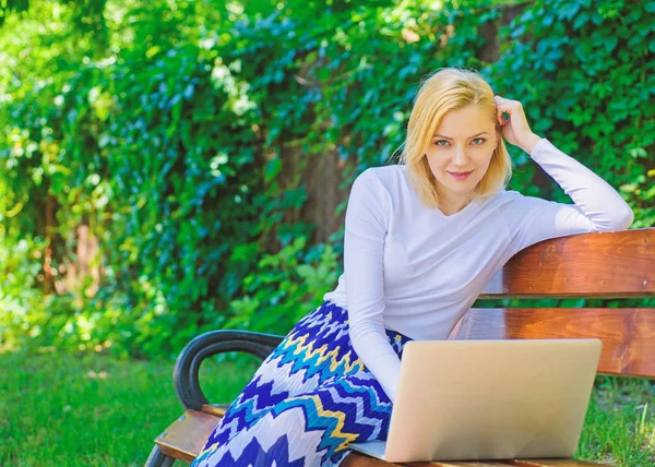 Advantages and disadvantages of becoming freelancer. Lady freelancer working in park. Freelance benefits. Woman with laptop works outdoor, green nature background. Girl sit bench with notebook