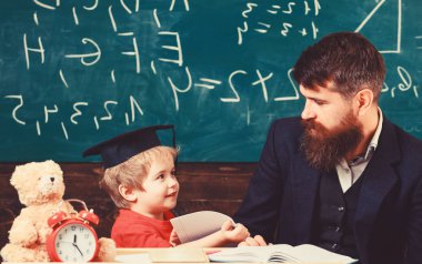 Çocuk mutlu çalışmalar öğretmen, evde ile ayrı ayrı. Bireysel eğitim kavramı. Sakal, oğlum, küçük çocuk öğretmen öğretir Peder. Öğretmen ve öğrenci kolej, kara tahta arka plan içinde