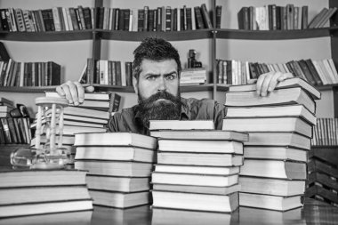 Öğretmen ya da öğrenci sakallı defocused kitaplar ile masada oturur. Kitaplığı'nda, eğitim sırasında kitaplar, kitap rafı arka plan üzerinde yığınları arasında ciddi bir yüz kişi. Kazık kavramı