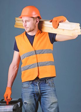 Ustalığının kavramı. Marangoz, woodworker, işçi, Oluşturucu meşgul yüz taşıdığı ahşap kirişler omuz üzerinde. Dostum, tamirci kask, kask içinde tutan araç kutusu ve ahşap kirişler, gri arka plan